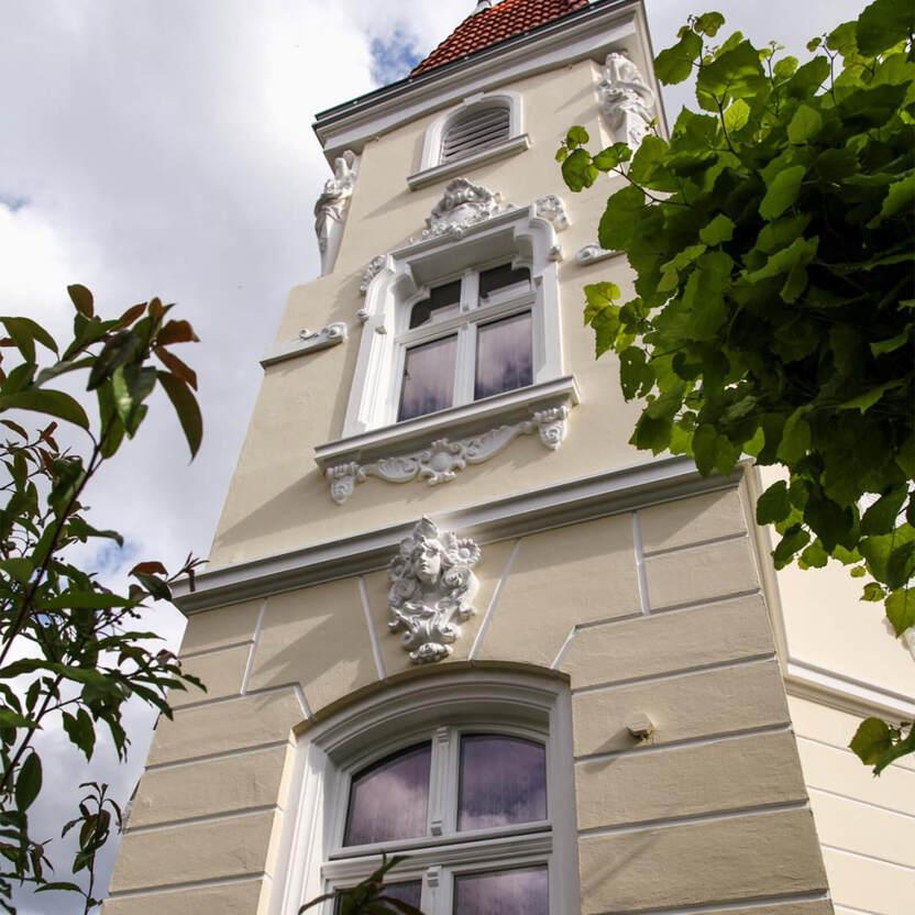 Fassade eines hellen Gebäudes mit verzierten Fenstern und Skulpturen