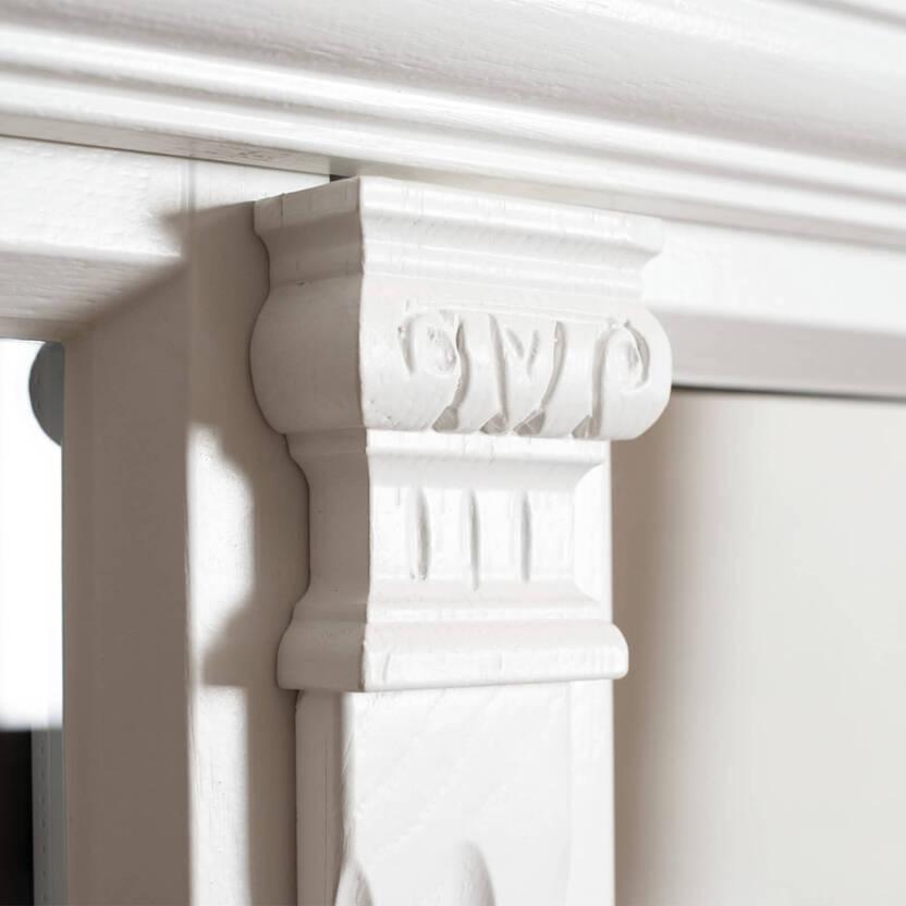 Weißes, verziertes Säulenelementen an einem Fensterrahmen