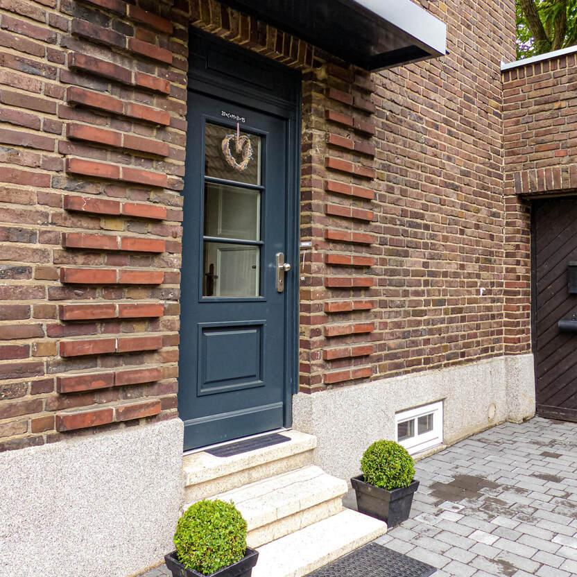 Blaue Haustür mit Glasfenster und Herzkranz