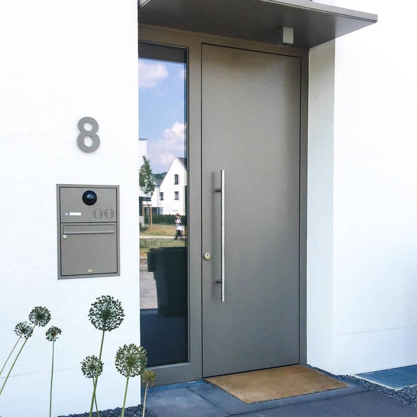 Moderner Hauseingang mit grauer Tür und langem Griff