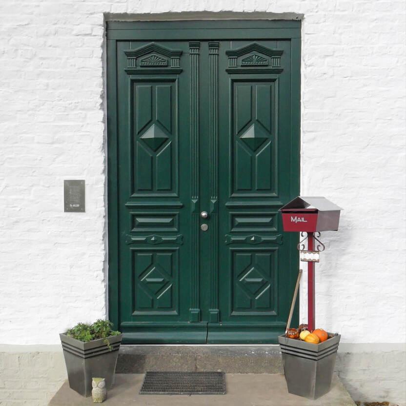 Dunkelgrüne Doppeltür mit dekorativen Reliefs