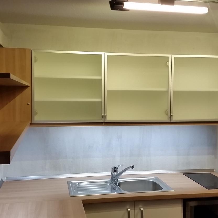 Funktionale maßgefertigte Küchenzeile Kompakte Küchenzeile mit cremefarbenen Oberschränken, Holzarbeitsfläche, Einbauspüle und Induktionskochfeld. Effizient gestaltet für Küchen nach Maß.