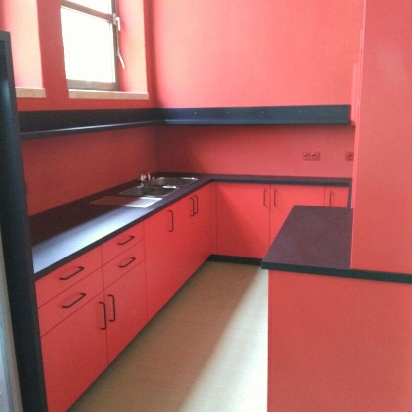 Maßgeschneiderte Küche in lebhaftem Rot Kompakte Ecke einer maßgefertigten Küche in kräftigem Rot mit eingebauter Spüle und reichlich Stauraum, perfekt für stilvolle Küchen nach Maß.