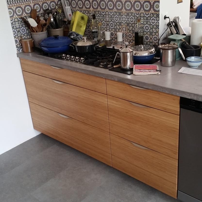 Küchenzeile mit sechs Schubladen, Gasherd, bunter Fliesenrückwand und grauer Arbeitsplatte