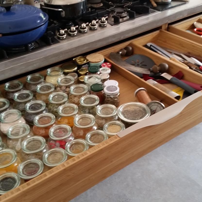 Offene Küchenschubladen mit vielen Gewürzgläsern, Kochwerkzeug und Besteckeinsätzen