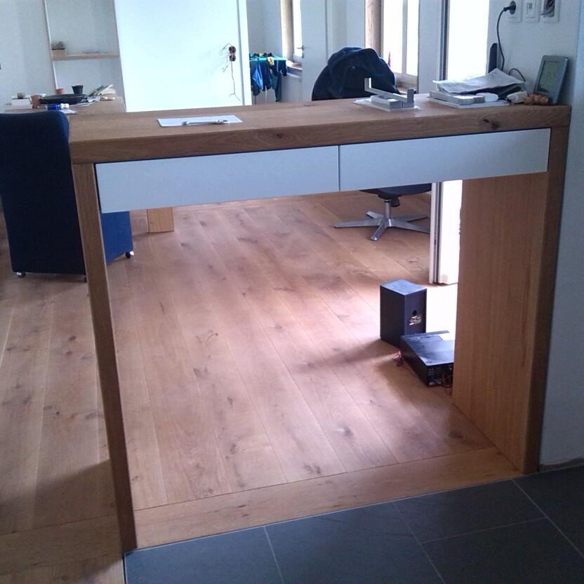 Maßgeschneiderter Holztresen mit zwei weißen Schubladen als Raumteiler zwischen zwei Zimmern