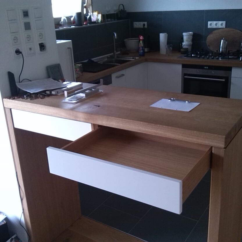 Massiver Küchentresen mit weißer Schublade vor moderner Einbauküche mit Holzarbeitsplatte
