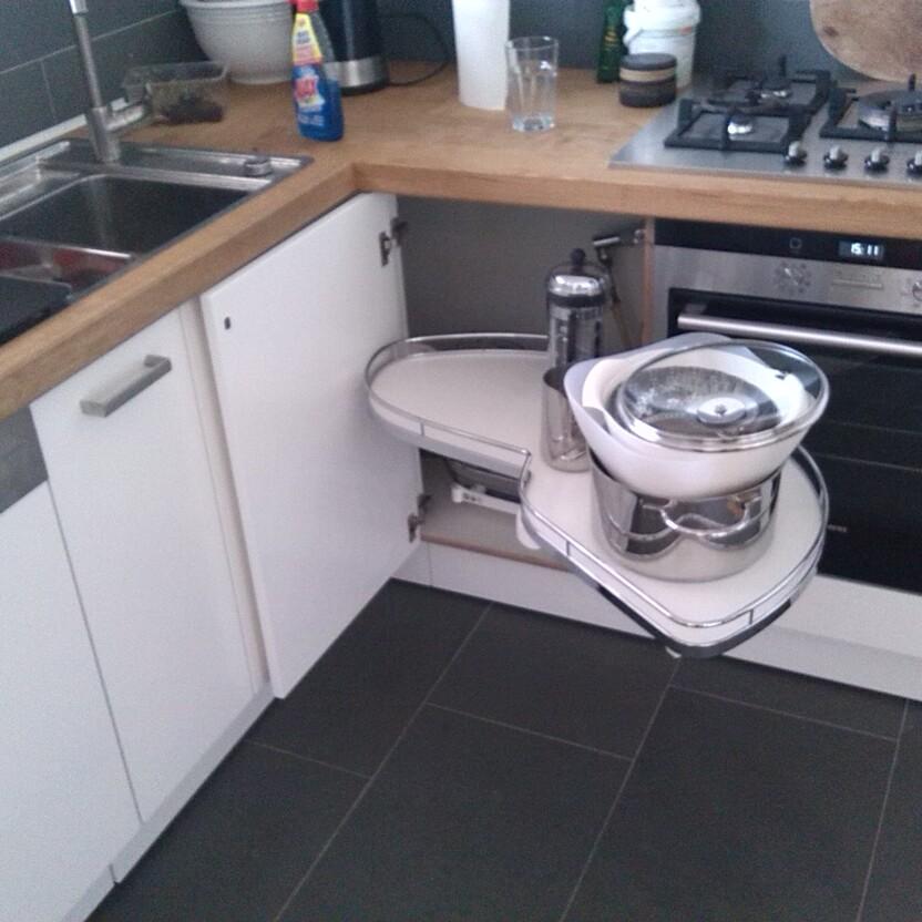 Geöffneter Kücheneckschrank mit ausziehbarem Rondell und Töpfen neben Spüle und Herd