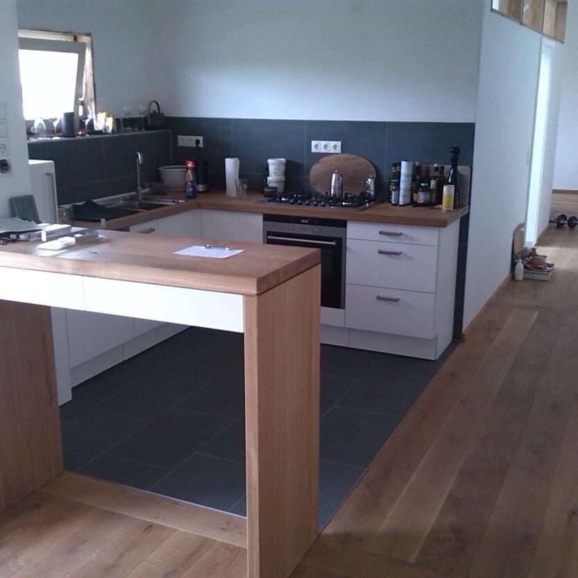 L-förmige Einbauküche mit Gasherd, Spüle und Massivholztresen als Raumteiler im Wohnbereich