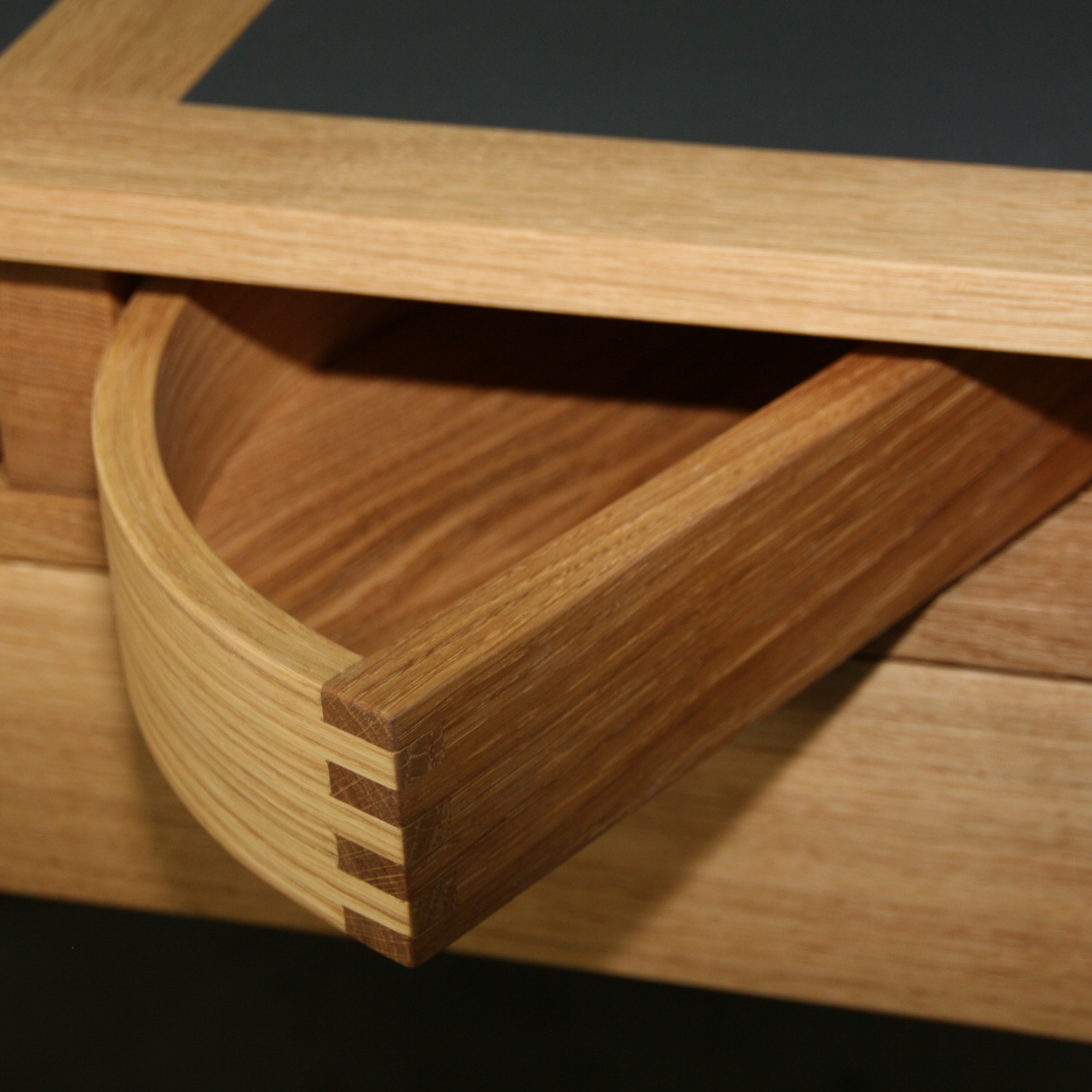 Detailaufnahme einer eleganten, runden Schublade aus Holz, meisterhaft gefertigt, zeigt die Präzision und Kreativität im Möbelbau.