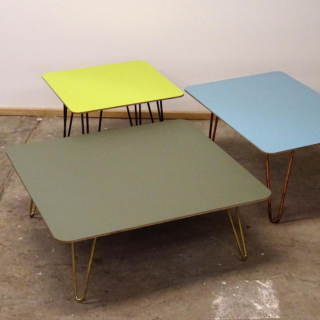 Drei stilvolle Couchtische aus Linoleum in Olive, Hellblau und Limettengrün, jeweils mit eleganten, kupferfarbenen Beinen.