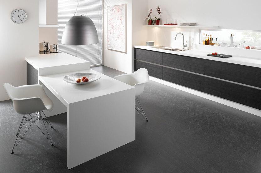 Impression einer einzeiligen K&uuml;chengestaltung in schwarz-wei&szlig; mit Esstisch f&uuml;r Zwei