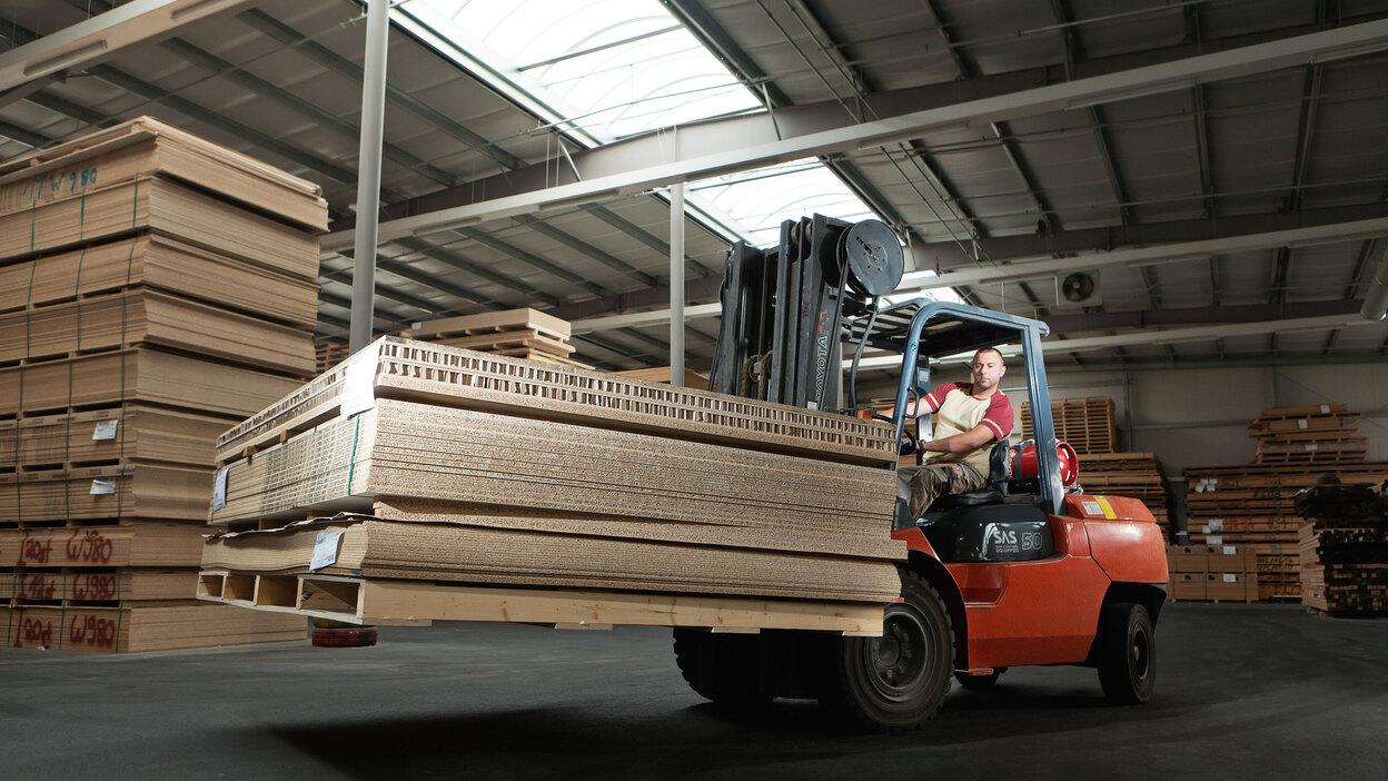 Gabelstapler transportiert Holzpaletten Gabelstapler transportiert Holz und Holzpaletten in Lager