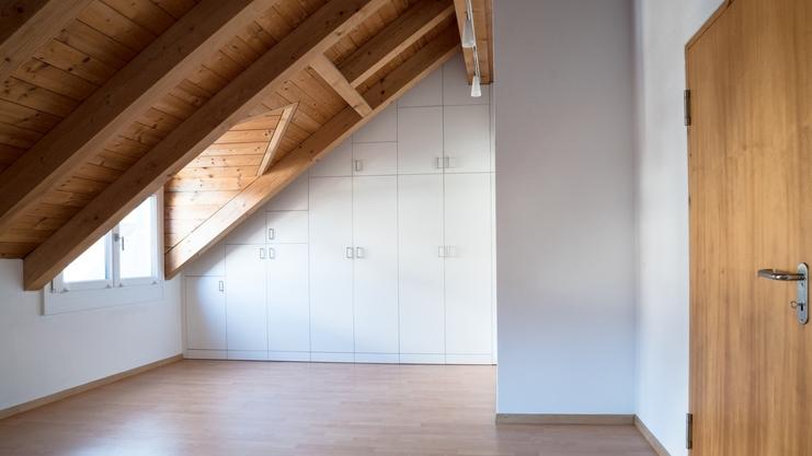 Nischenlösung für Einbauschrank an holzbelassener Dachschräge Nischenlösung für weißen Einbauschrank mit Schubladen und Türen an in dunklem Holz belassener Dachschräge