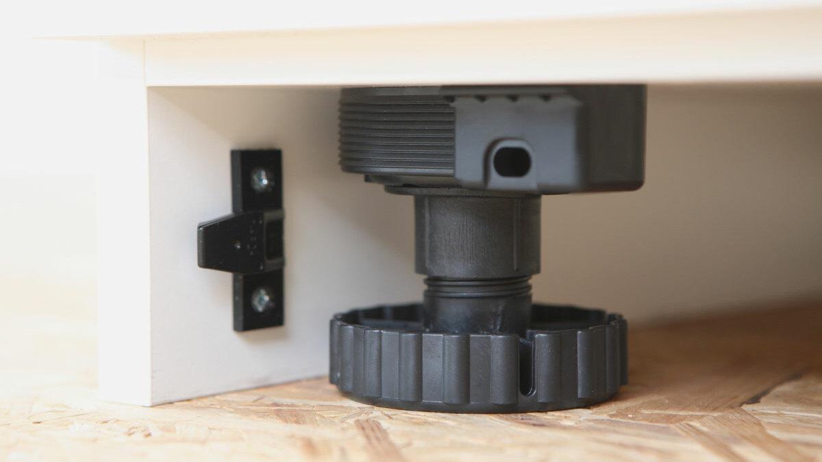Detailaufnahme eines verstellbaren schwarzen Bodensockels mit Schraubmechanismus