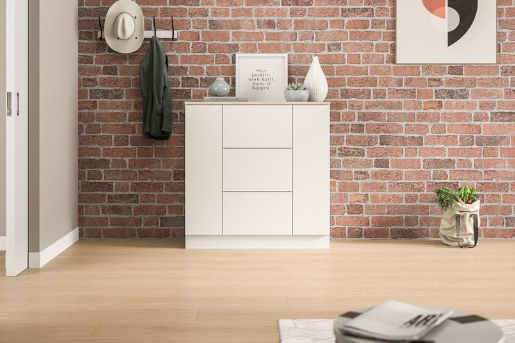 Moderne Kommode nach Maß vor einer Backsteinwand im Eingangsbereich. Eine schlichte, weiße Kommode nach Maß, die sich gegen eine rustikale Backsteinwand abhebt, bietet Stauraum und eine stilvolle Ablagefläche im Eingangsbereich.